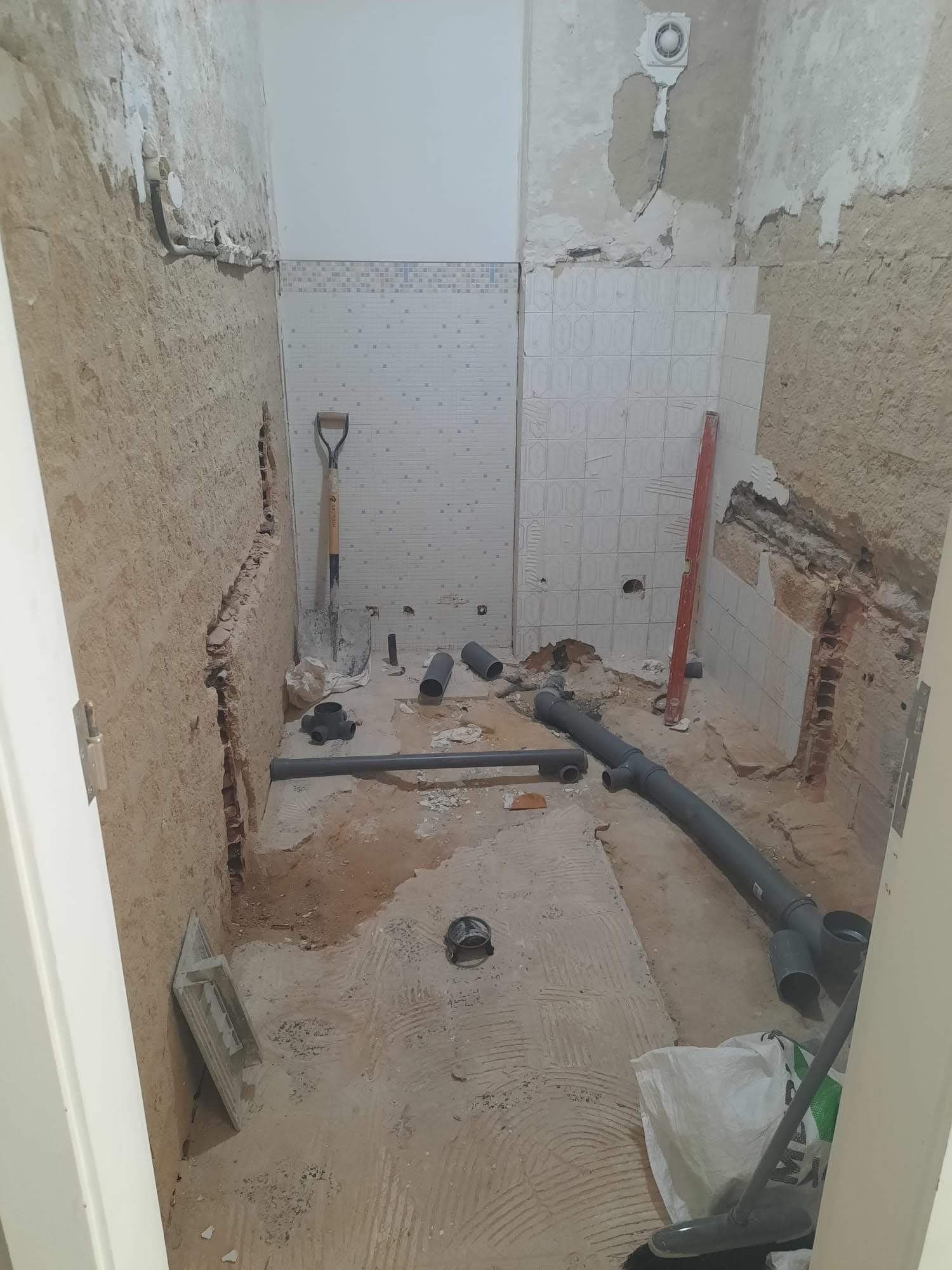 Casa de banho em obra com paredes e canalização à vista